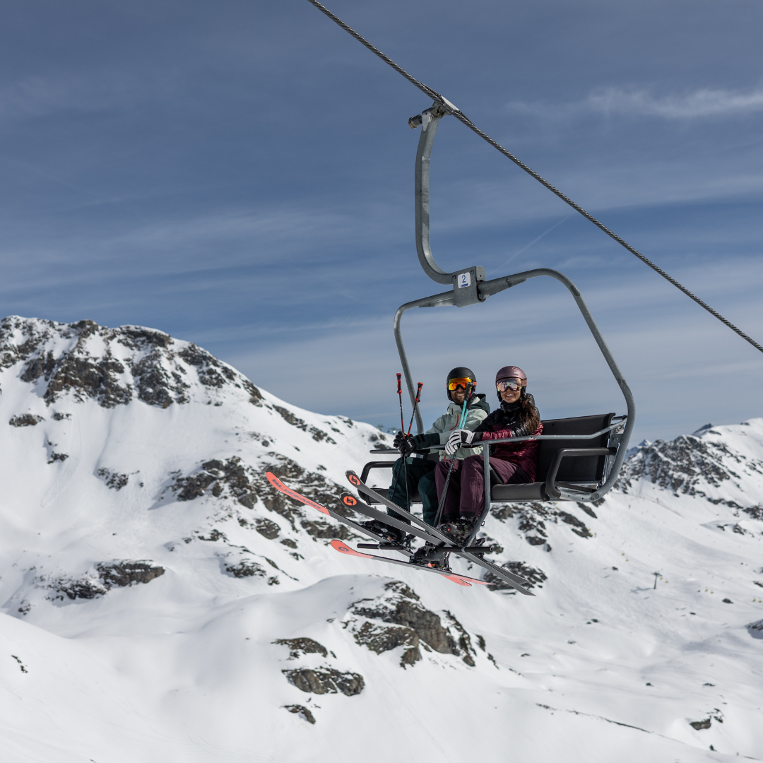 Man en vrouw in skilift met uitrusting van skiverhuur in nederland